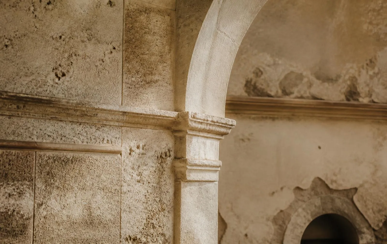 Weathered travertine archway detail in soft morning light