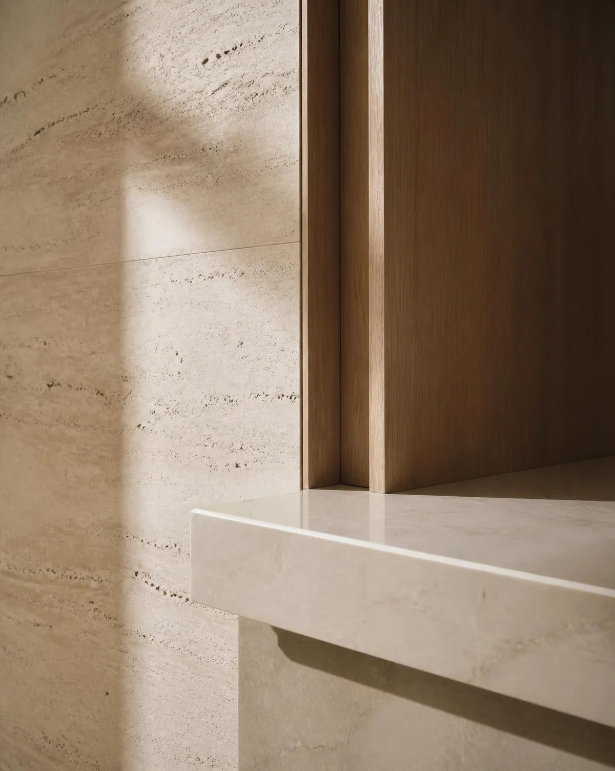 Travertine wall, honed marble ledge and bespoke oak joinery in soft daylight